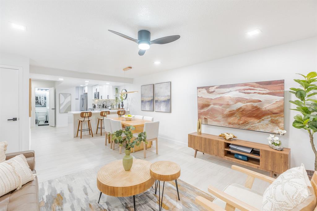 An open-concept living and dining area features light wood flooring, modern furniture, and white walls — 701 S ATLANTIC AVENUE UNIT UT21, NEW SMYRNA BEACH, FL