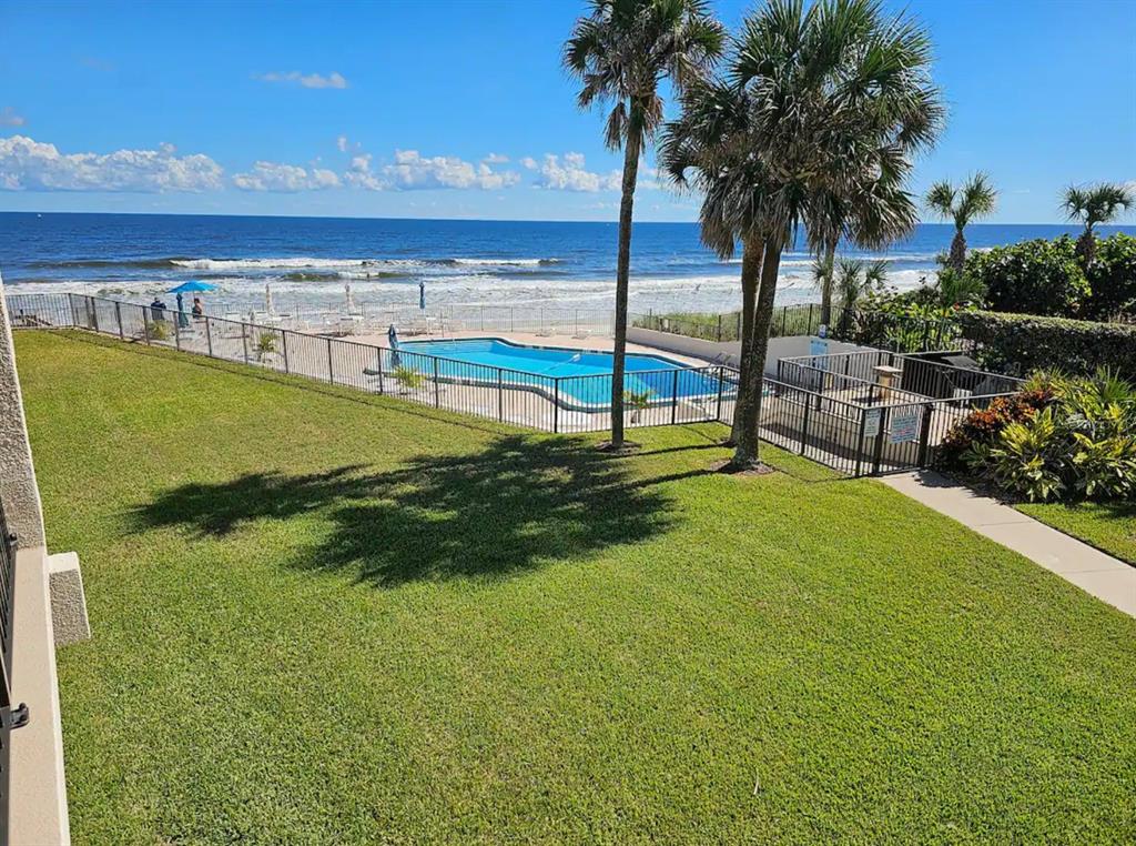 An elevated view of a grassy lawn, a swimming pool, and the ocean beyond — 701 S ATLANTIC AVENUE UNIT UT21, NEW SMYRNA BEACH, FL