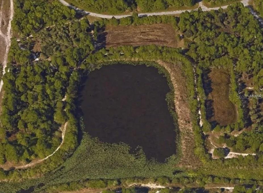 An aerial view shows a vacant, irregularly shaped plot of land adjacent to a highway — KIMBERLY DRIVE, NORTH PORT, FL