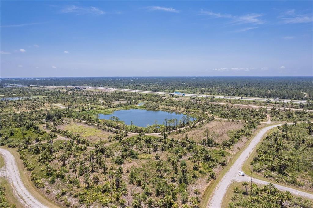 An aerial view of a pond surrounded by undeveloped land and a nearby highway — KIMBERLY DRIVE, NORTH PORT, FL