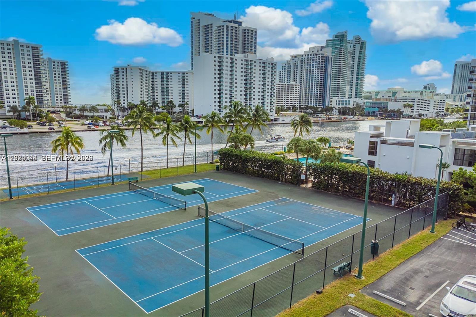 An elevated view shows two blue tennis courts next to a waterway and high-rise buildings — 800 Parkview Dr # 527, Hallandale Beach FL 33009, HALLANDALE BEACH, FL