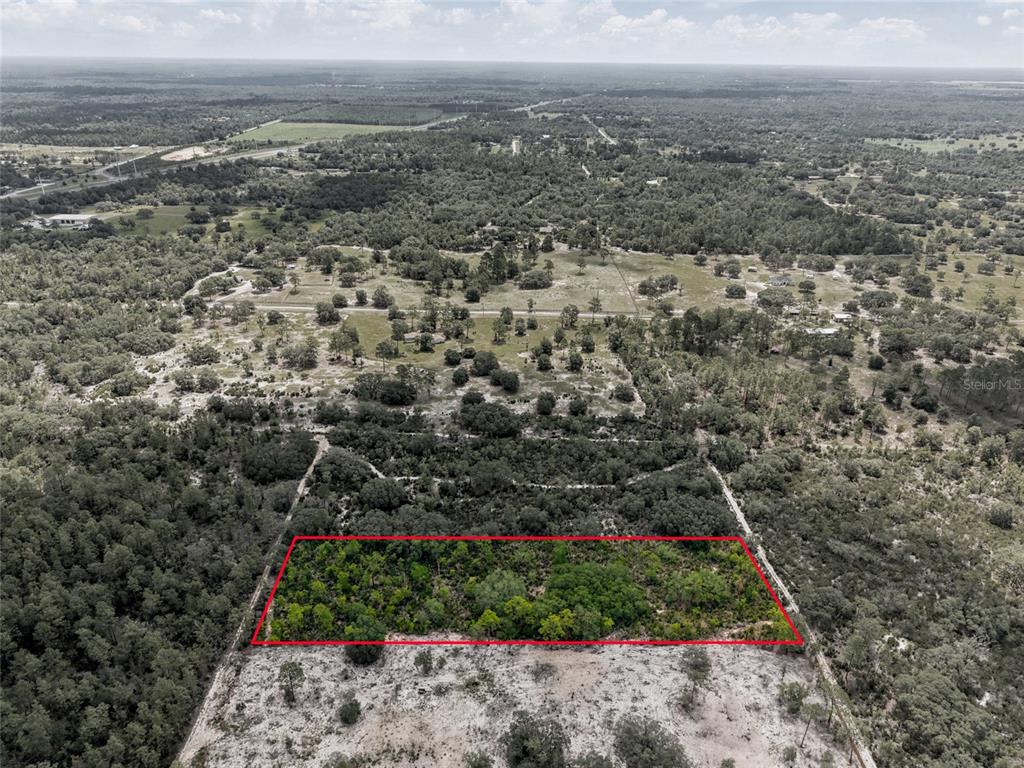 An aerial view shows a rectangular plot of land outlined in red amidst wooded terrain — Lot 00 NE 56TH ST, BRONSON, FL