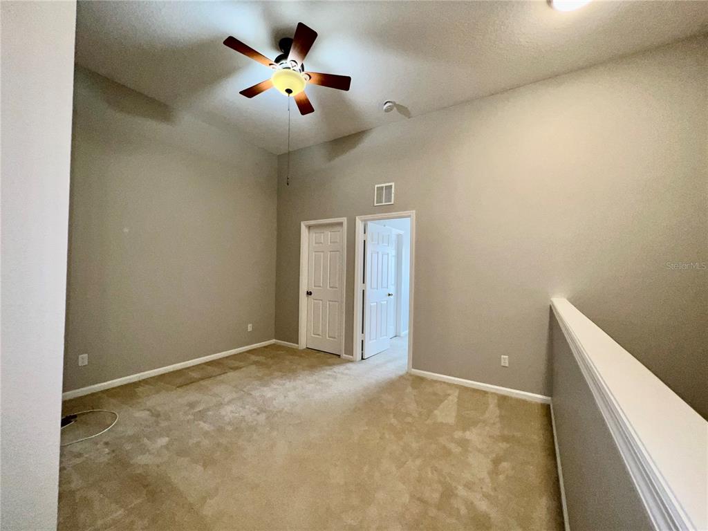 An empty room with beige carpet, gray walls, a ceiling fan, and two white doors — 2648 GALLIANO CIRCLE, WINTER PARK, FL