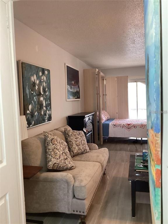 A living room with a beige sofa, a black cabinet, and a bed in the background — 7701 STARKEY ROAD UNIT 704, SEMINOLE, FL