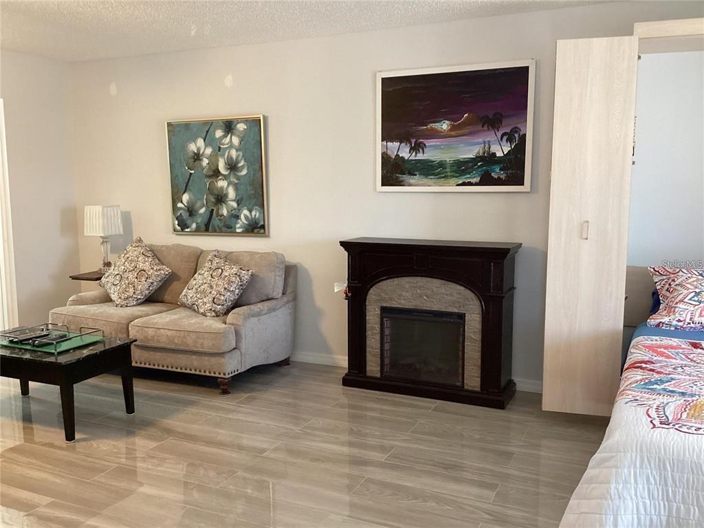 A living area features a sofa, fireplace, and bed on light-colored wood-look tile flooring — 7701 STARKEY ROAD UNIT 704, SEMINOLE, FL