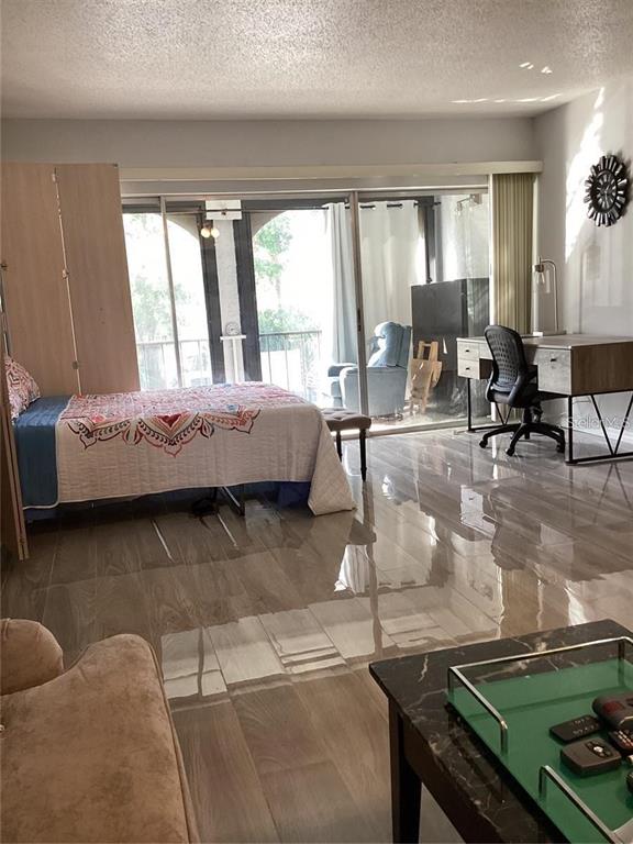A bedroom with a bed, desk, and sliding glass doors leading to a balcony — 7701 STARKEY ROAD UNIT 704, SEMINOLE, FL
