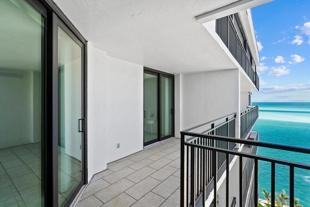 A bedroom with a tiled floor, a quilt-covered bed, and an attached bathroom — 4822 OCEAN BOULEVARD UNIT 11E, SARASOTA, FL