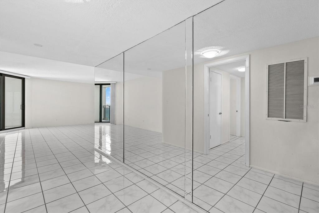 A room with white tiled floors and a large mirrored wall reflecting a hallway — 4822 OCEAN BOULEVARD UNIT 11E, SARASOTA, FL