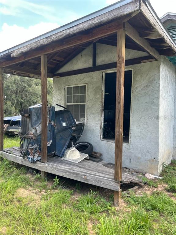 A small, weathered shed with a wooden porch, a window, and debris stored outside — 108 PLANTATION LANE, WAVERLY, FL