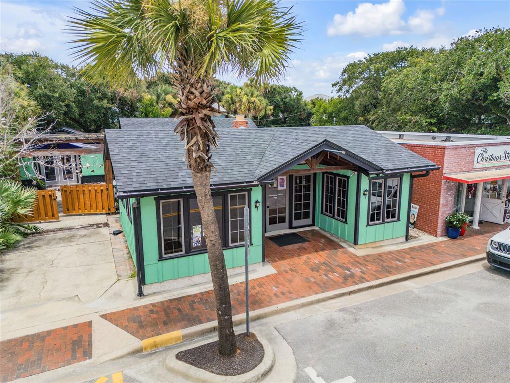 A green, single-story commercial building with a brick walkway and a palm tree in front — 304 FLAGLER AVENUE, NEW SMYRNA BEACH, FL