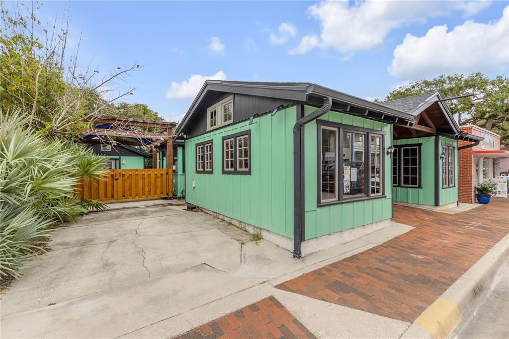 An aerial view shows a green building with a brick storefront and adjacent parking lot — 304 FLAGLER AVENUE, NEW SMYRNA BEACH, FL