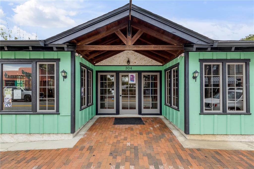 A mint green building with dark trim sits next to a brick walkway and driveway — 304 FLAGLER AVENUE, NEW SMYRNA BEACH, FL