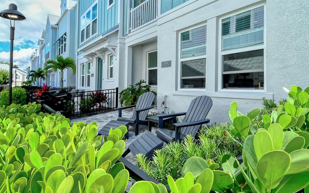 A patio with two dark chairs sits in front of a light blue townhouse exterior — 2300 LINDSTROM STREET, SARASOTA, FL