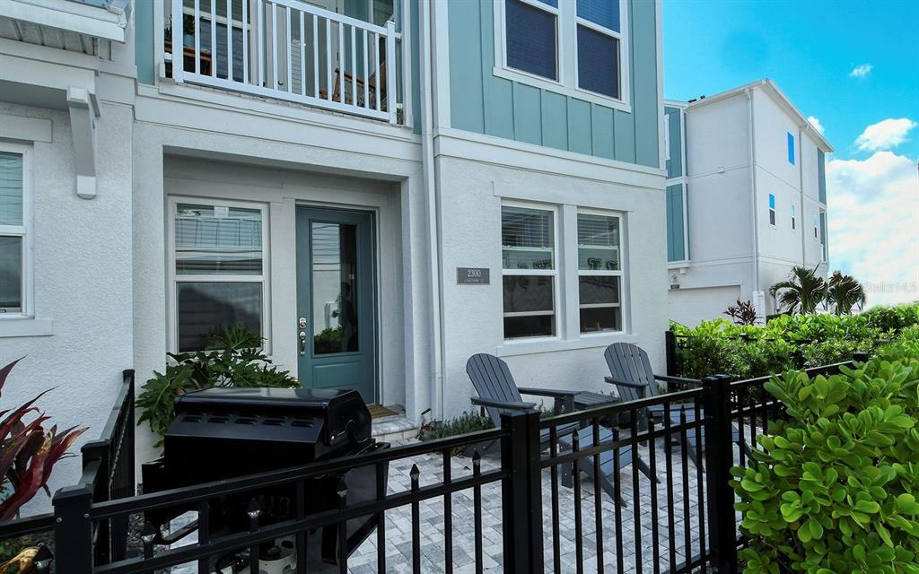 A teal front door and patio with a grill and chairs at a townhouse entrance — 2300 LINDSTROM STREET, SARASOTA, FL