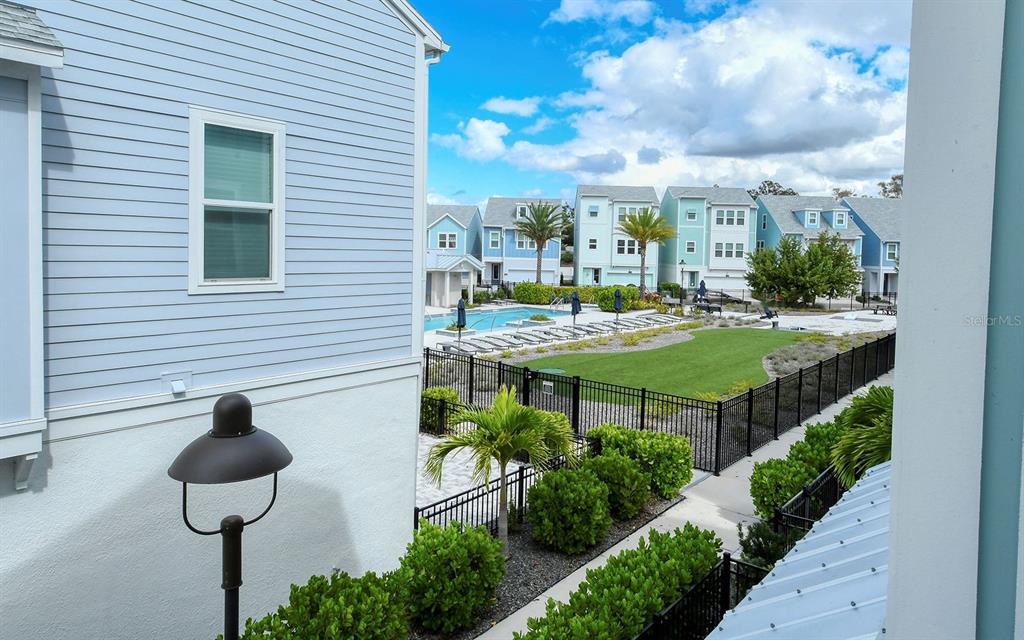 An elevated view shows a swimming pool and green space surrounded by colorful townhouses — 2300 LINDSTROM STREET, SARASOTA, FL