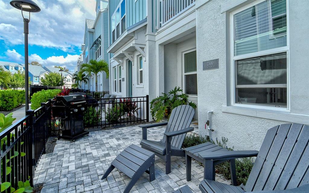 A paved patio features two gray Adirondack chairs, a matching ottoman, and a black grill — 2300 LINDSTROM STREET, SARASOTA, FL