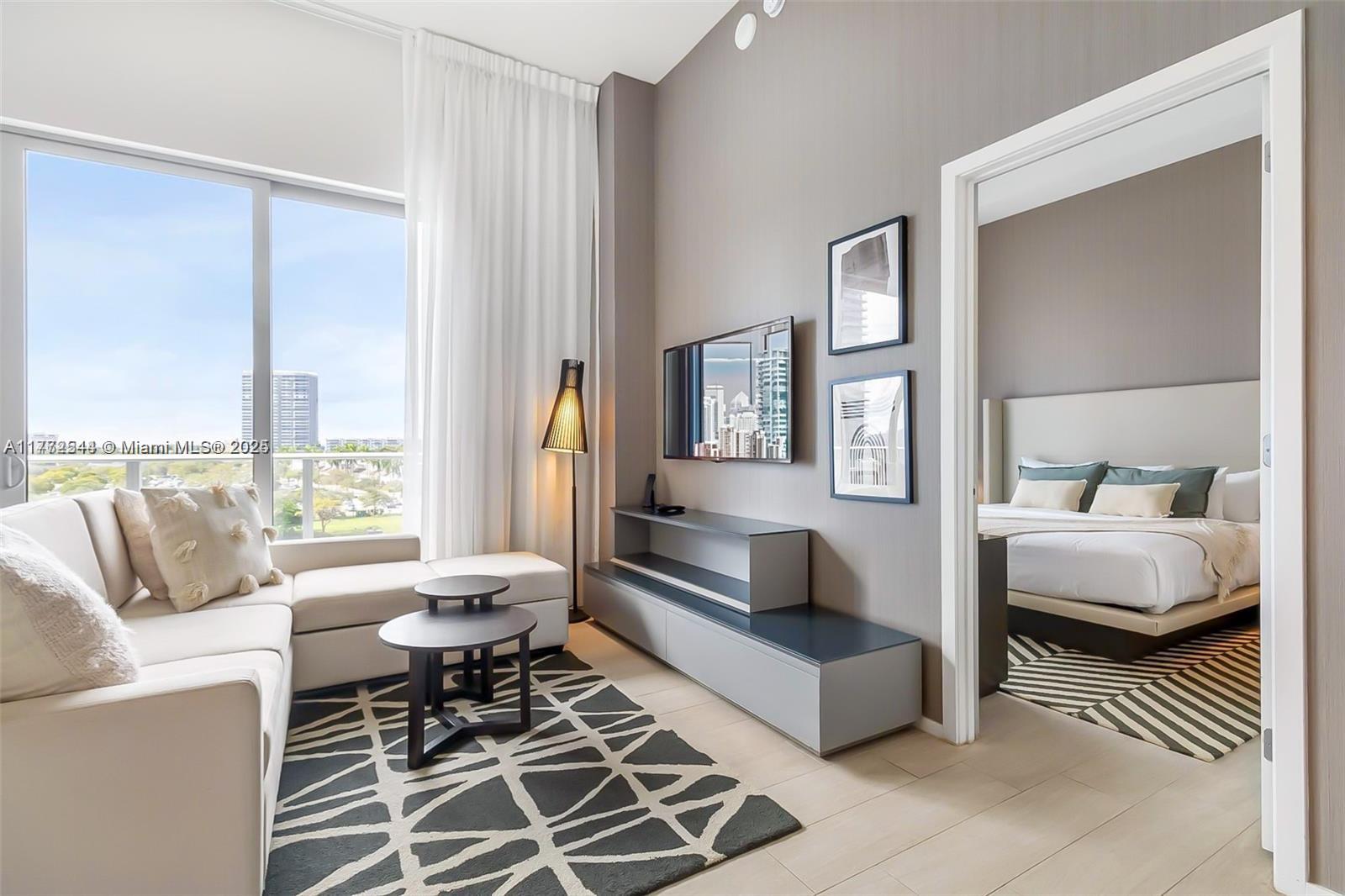A living room with a sectional sofa, television, and an adjacent bedroom visible through a doorway — 4010 S Ocean Dr # R406, Hollywood FL 33019, HOLLYWOOD, FL
