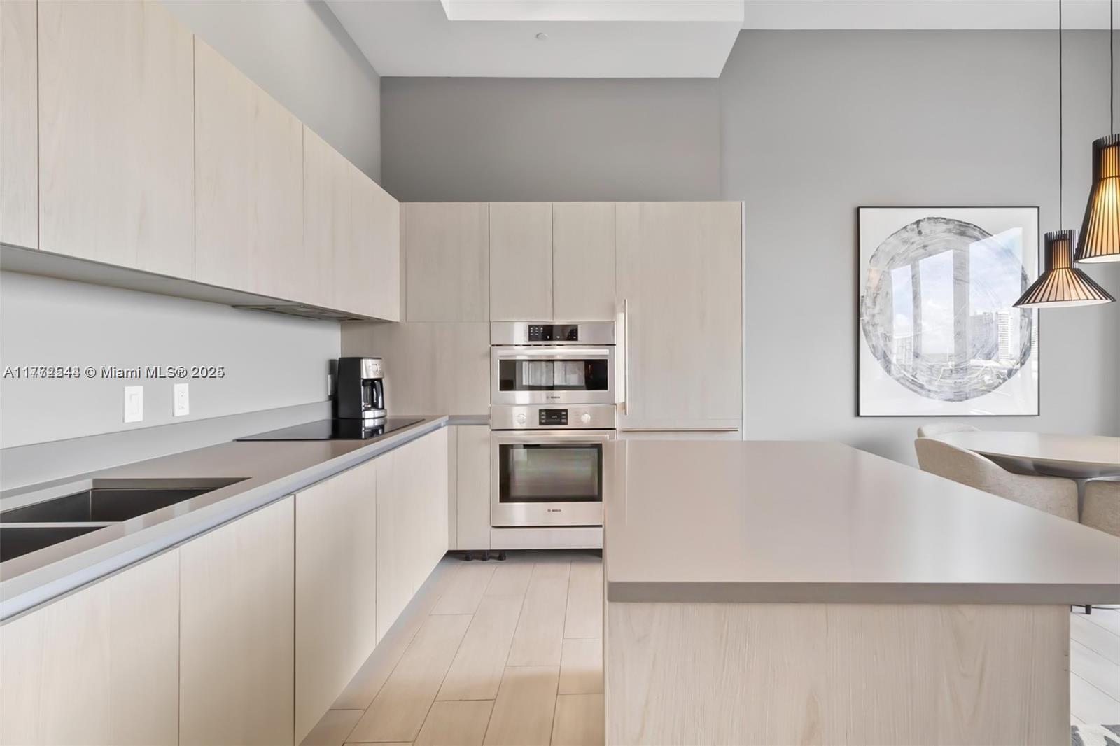 A modern kitchen features light wood cabinetry, stainless steel appliances, and a large central island — 4010 S Ocean Dr # R406, Hollywood FL 33019, HOLLYWOOD, FL