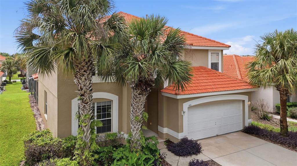 A two-story house with a tan stucco exterior, orange tile roof, and a two-car garage — 165 SEVILLA AVENUE, DAVENPORT, FL