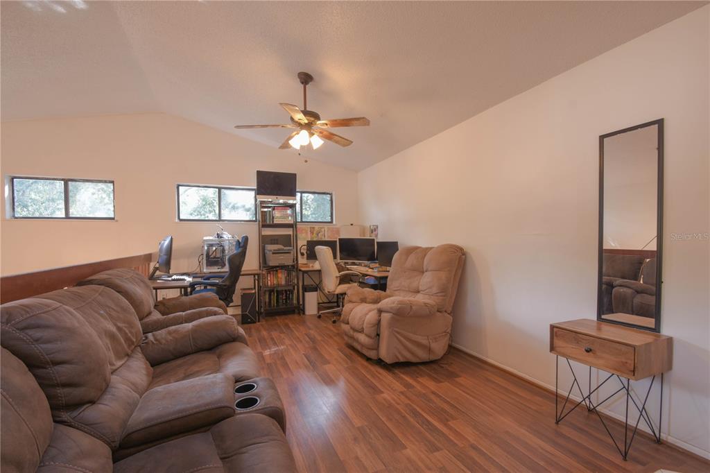 A living room features wood-look flooring, a vaulted ceiling with a fan, and office furniture — 321 KIRKCALDY DRIVE, WINTER SPRINGS, FL