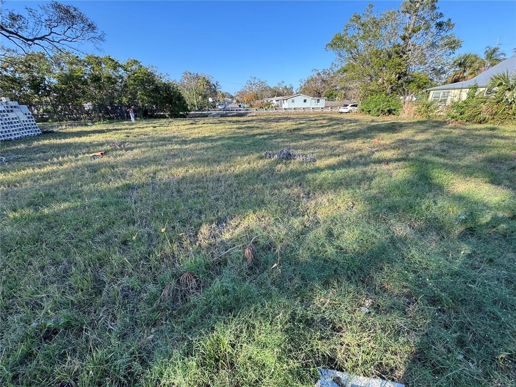 A vacant, grassy residential lot with trees and neighboring houses in the background — 26TH AVENUE S, ST PETERSBURG, FL