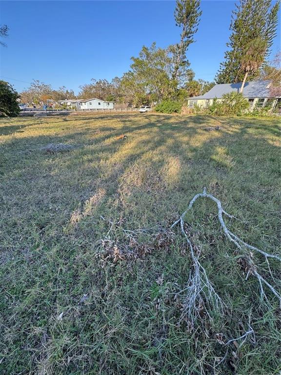 A grassy, vacant residential lot with a fallen tree branch in the foreground — 26TH AVENUE S, ST PETERSBURG, FL