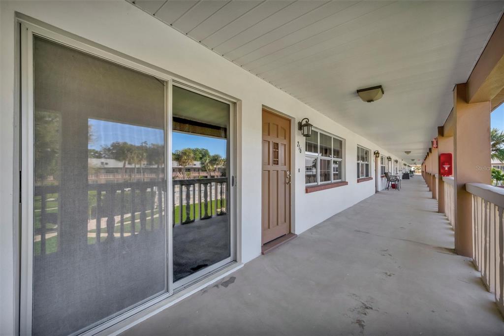 A covered outdoor walkway features a sliding glass door and a brown wooden entry door — 650 PINELLAS POINT DRIVE S UNIT 216, ST PETERSBURG, FL
