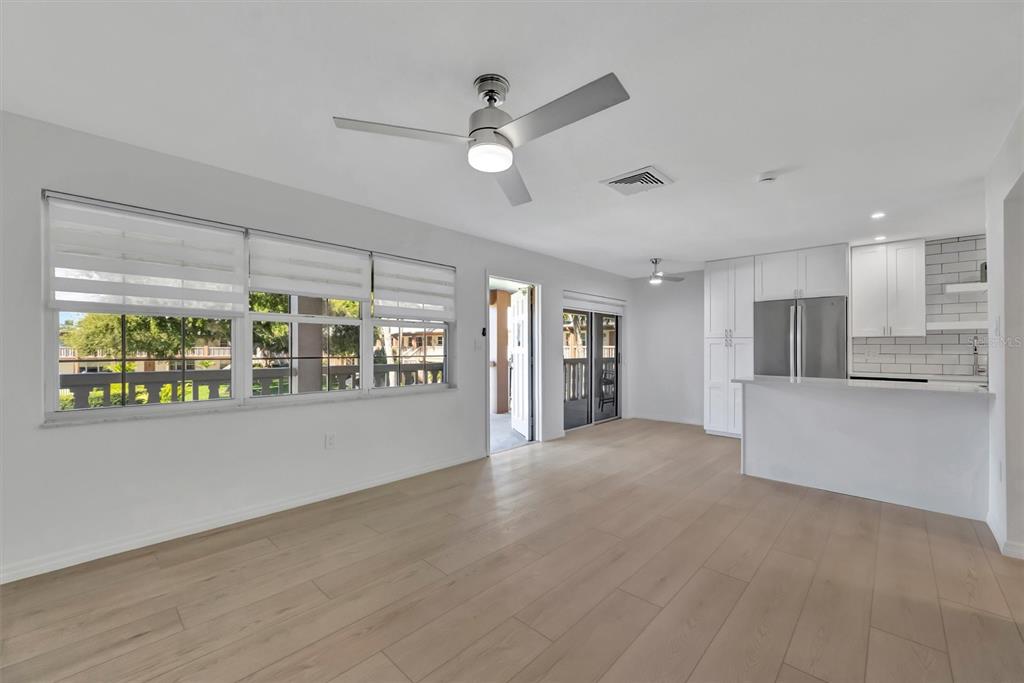 An open-concept living area with light wood floors, white cabinets, and a ceiling fan — 650 PINELLAS POINT DRIVE S UNIT 216, ST PETERSBURG, FL