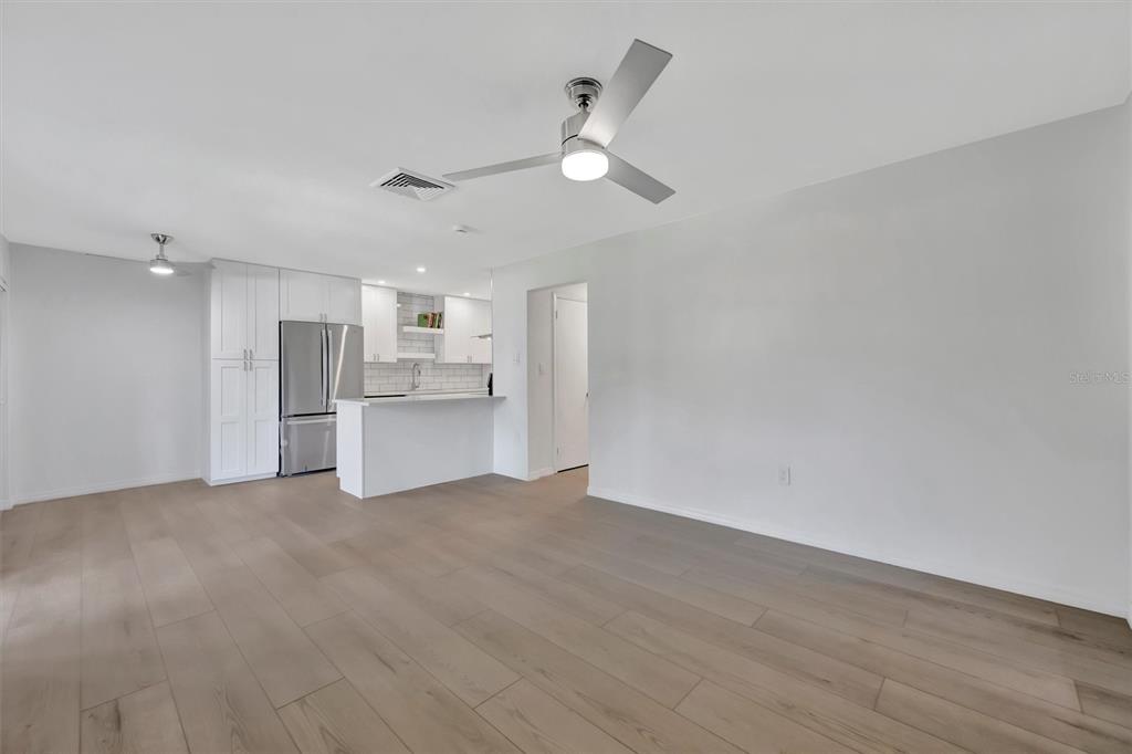 A bright, open-concept living area features light wood flooring, white walls, and a modern kitchen — 650 PINELLAS POINT DRIVE S UNIT 216, ST PETERSBURG, FL