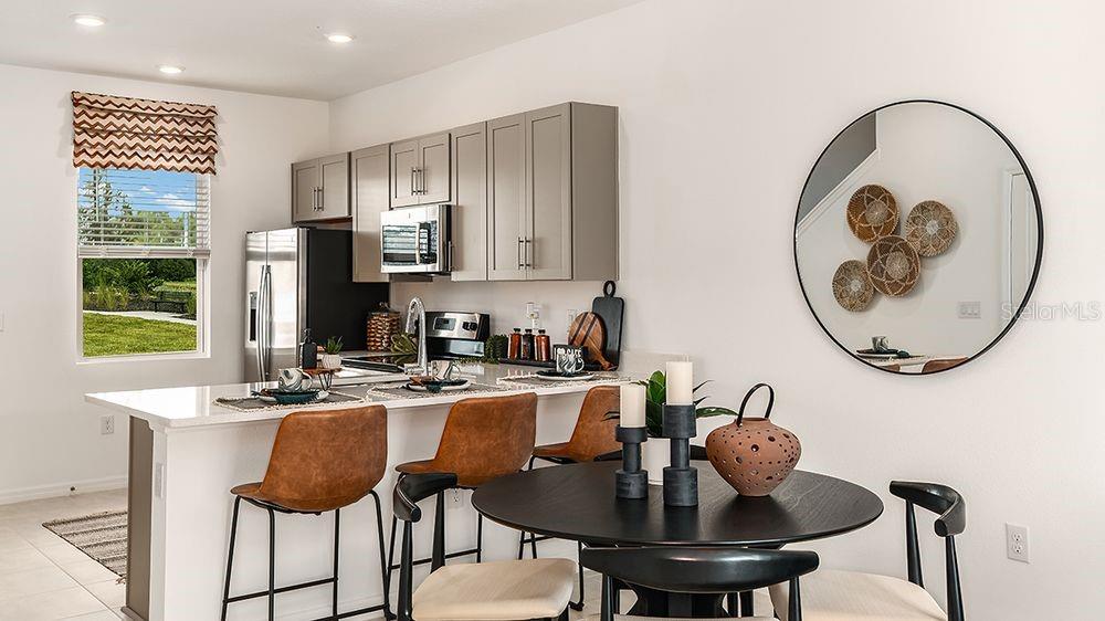 A kitchen with gray cabinets and a breakfast bar next to a small dining area — 10637 ORBIT TERRACE, SARASOTA, FL