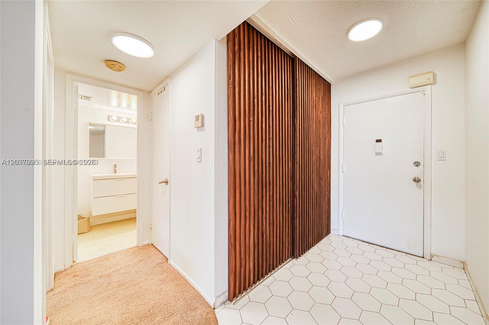 An entryway features a white door, a slatted wood closet, and a tiled floor — 1690 NE 191st St # 1, Miami FL 33179, MIAMI, FL