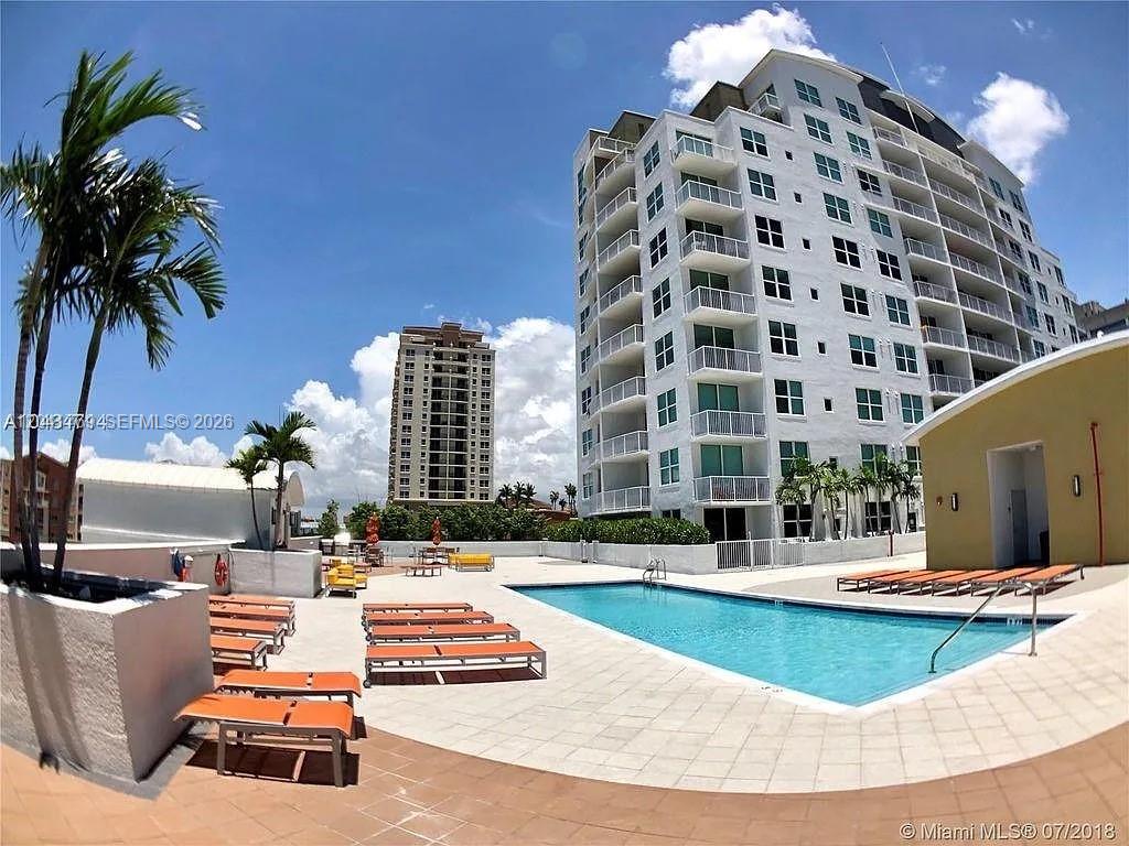 An outdoor swimming pool is surrounded by lounge chairs and a multi-story residential building — 3180 SW 22nd Ter, Miami FL 33145, MIAMI, FL