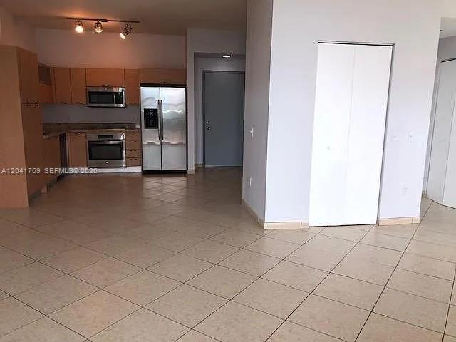 A kitchen with stainless steel appliances and tile flooring opens into a living area — 3180 SW 22nd Ter, Miami FL 33145, MIAMI, FL