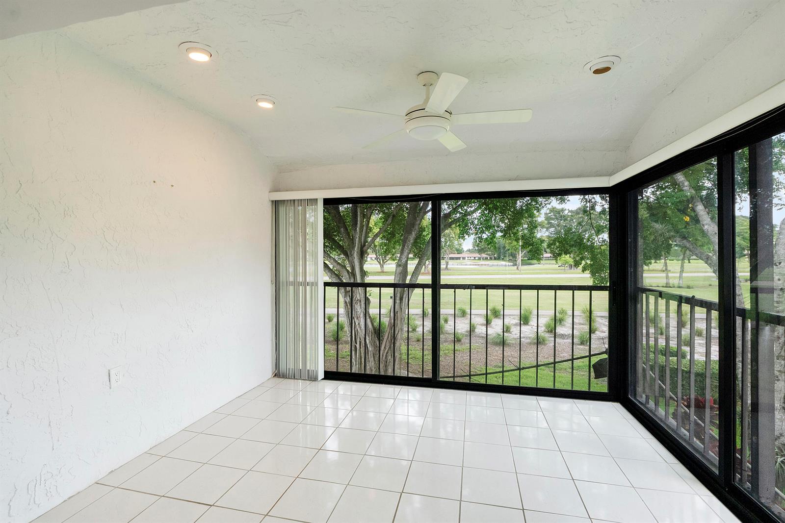 A sunroom with white tile floors, a ceiling fan, and large windows overlooking a golf course — 21852 Arriba # h, Boca Raton FL 33433, BOCA RATON, FL