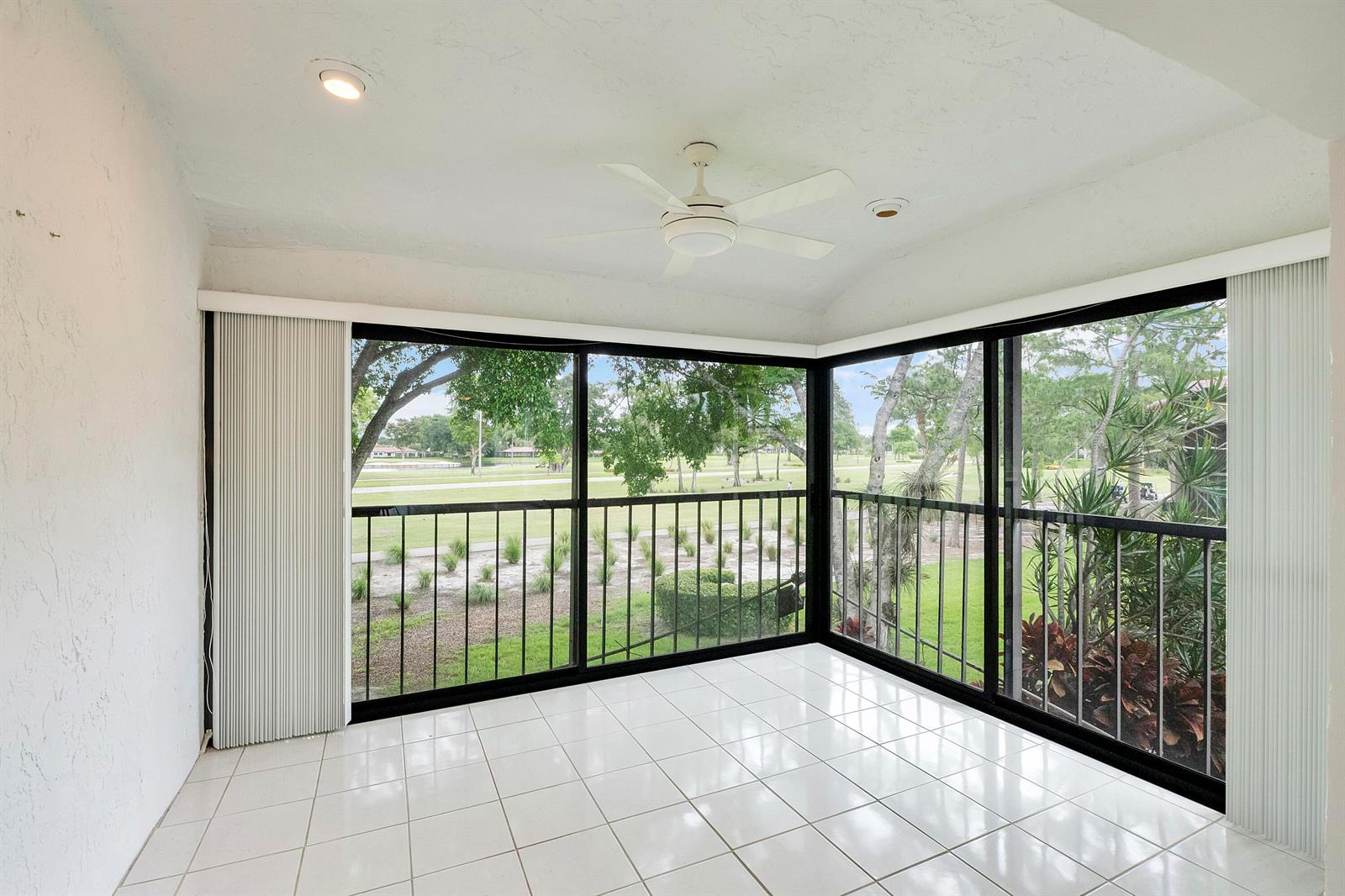 A sunroom with white tile flooring, a ceiling fan, and large windows overlooking a golf course — 21852 Arriba # h, Boca Raton FL 33433, BOCA RATON, FL
