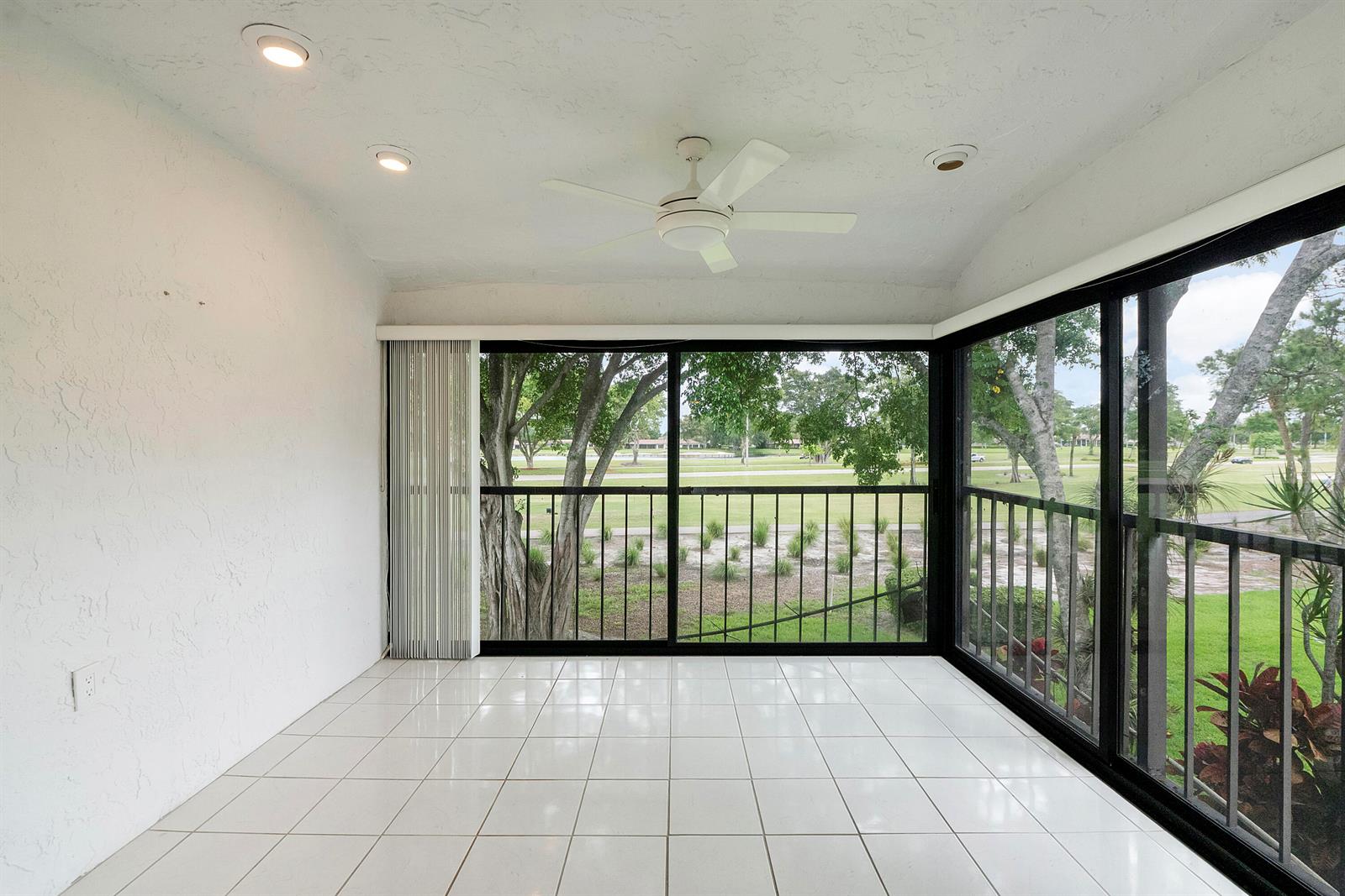 A sunroom with white tile floors, a ceiling fan, and large windows overlooking a golf course — 21852 Arriba # h, Boca Raton FL 33433, BOCA RATON, FL