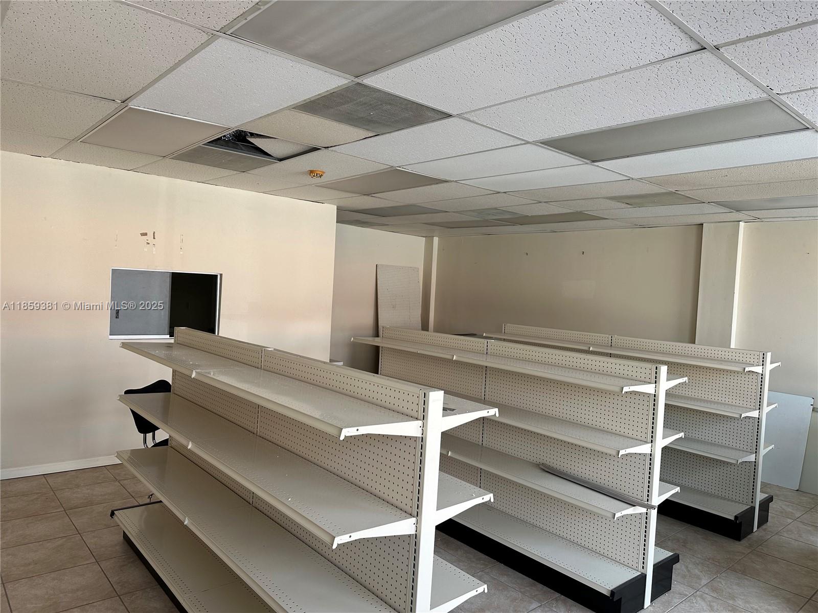 An empty retail space features white metal shelving units and a damaged drop ceiling — 455 SW 17th Ave, Miami FL 33135, MIAMI, FL