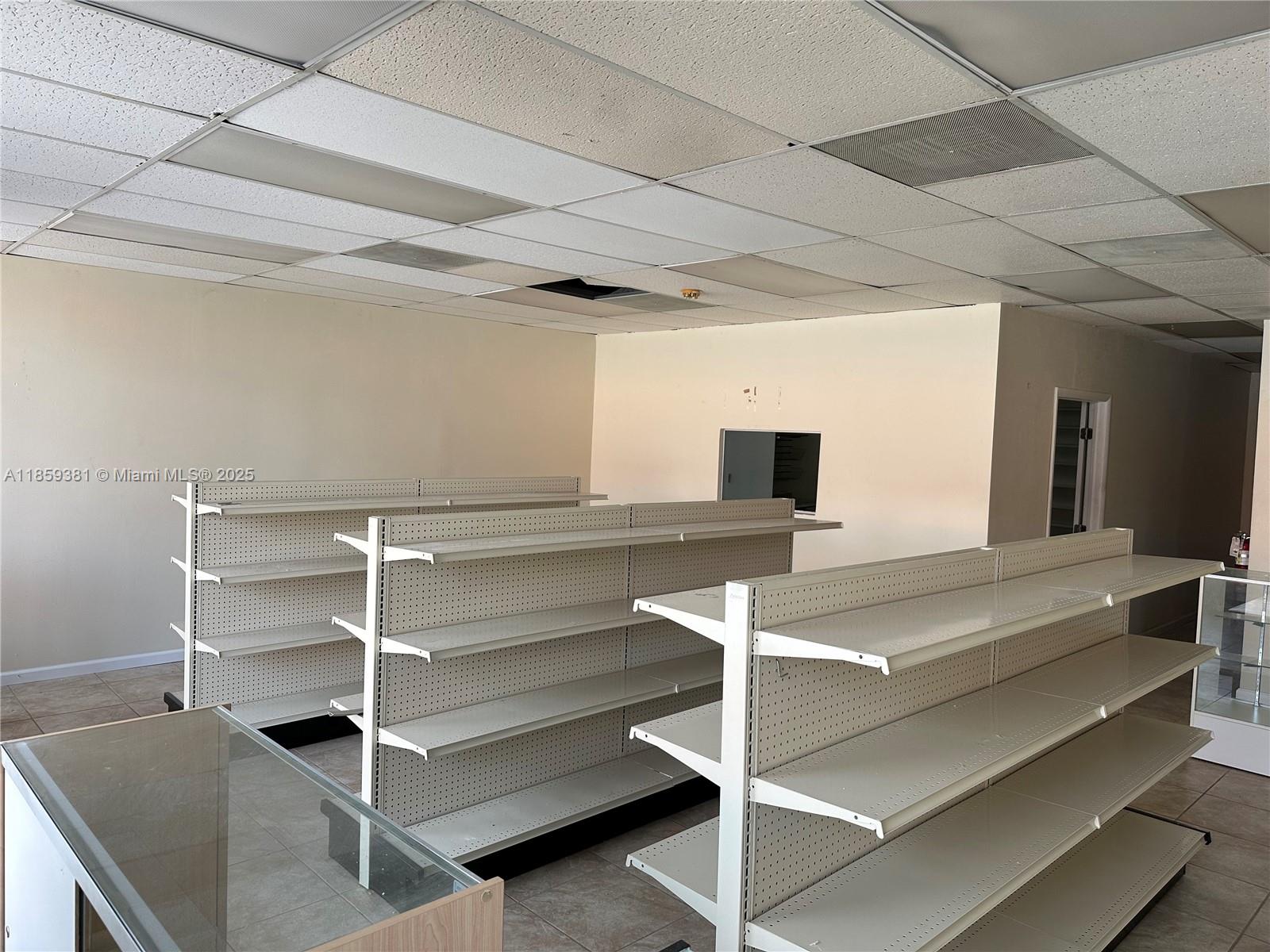 An empty retail space features rows of metal shelving units and a drop ceiling — 455 SW 17th Ave, Miami FL 33135, MIAMI, FL