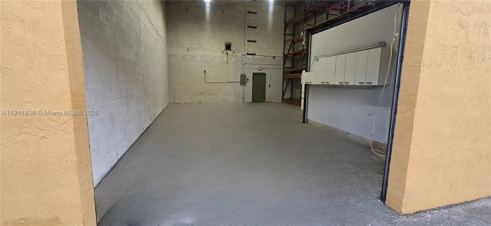 An empty warehouse space features concrete walls, a gray floor, and overhead storage shelving — 2954 W 84th St # 118, Hialeah FL 33018, HIALEAH, FL