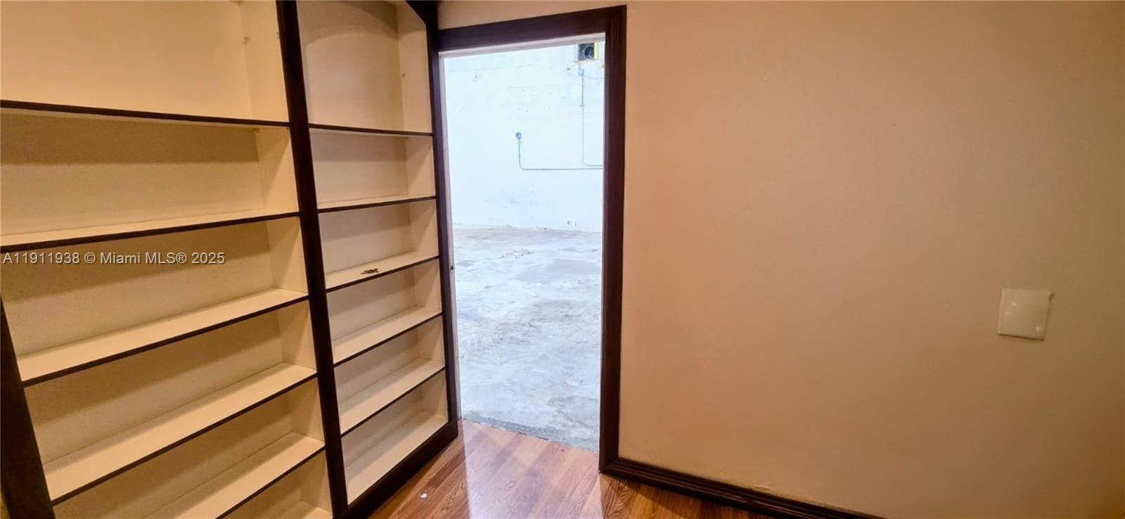A room features built-in wooden shelving units next to a doorway leading to an outdoor area — 2954 W 84th St # 118, Hialeah FL 33018, HIALEAH, FL