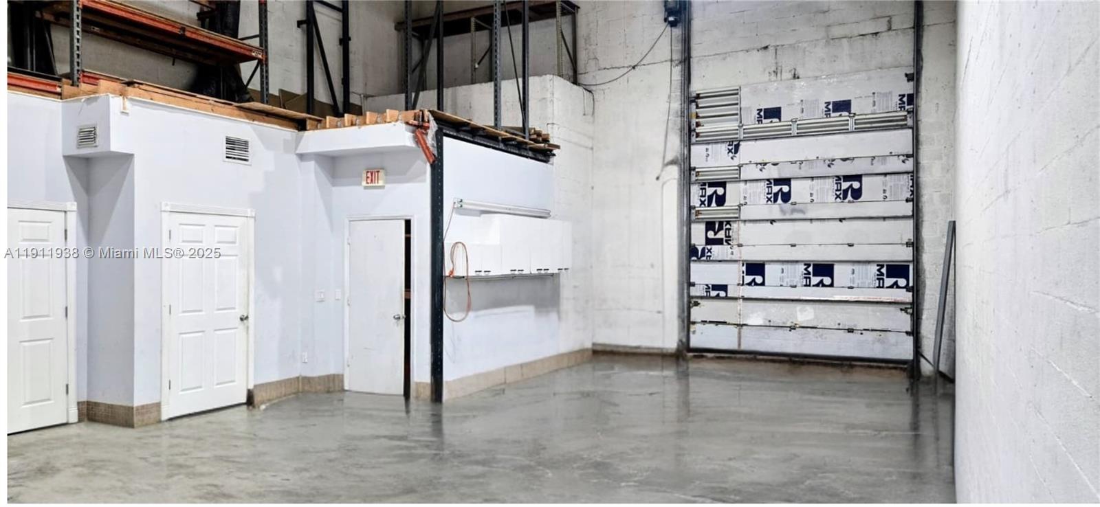 An industrial warehouse space features a concrete floor, white walls, two doors, and a roll-up door — 2954 W 84th St # 118, Hialeah FL 33018, HIALEAH, FL
