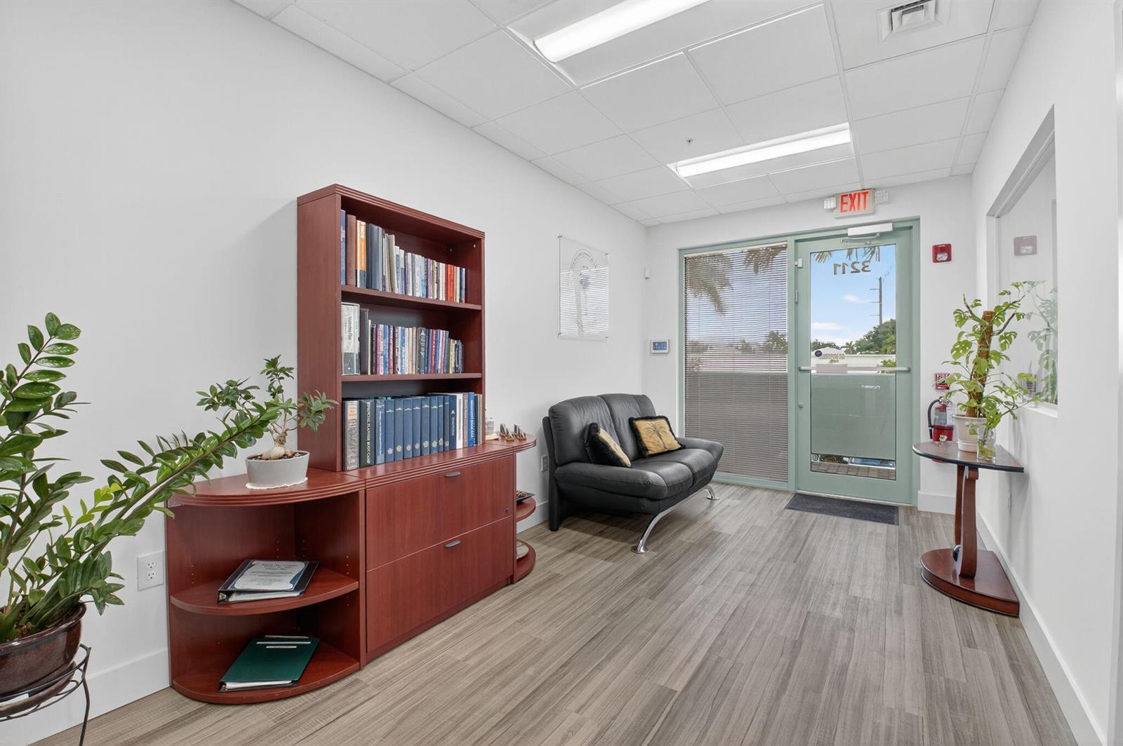 A waiting room features a dark wood bookshelf, a black sofa, and a glass door — 7700 Congress Avenue # 3211, Boca Raton FL 33487, BOCA RATON, FL