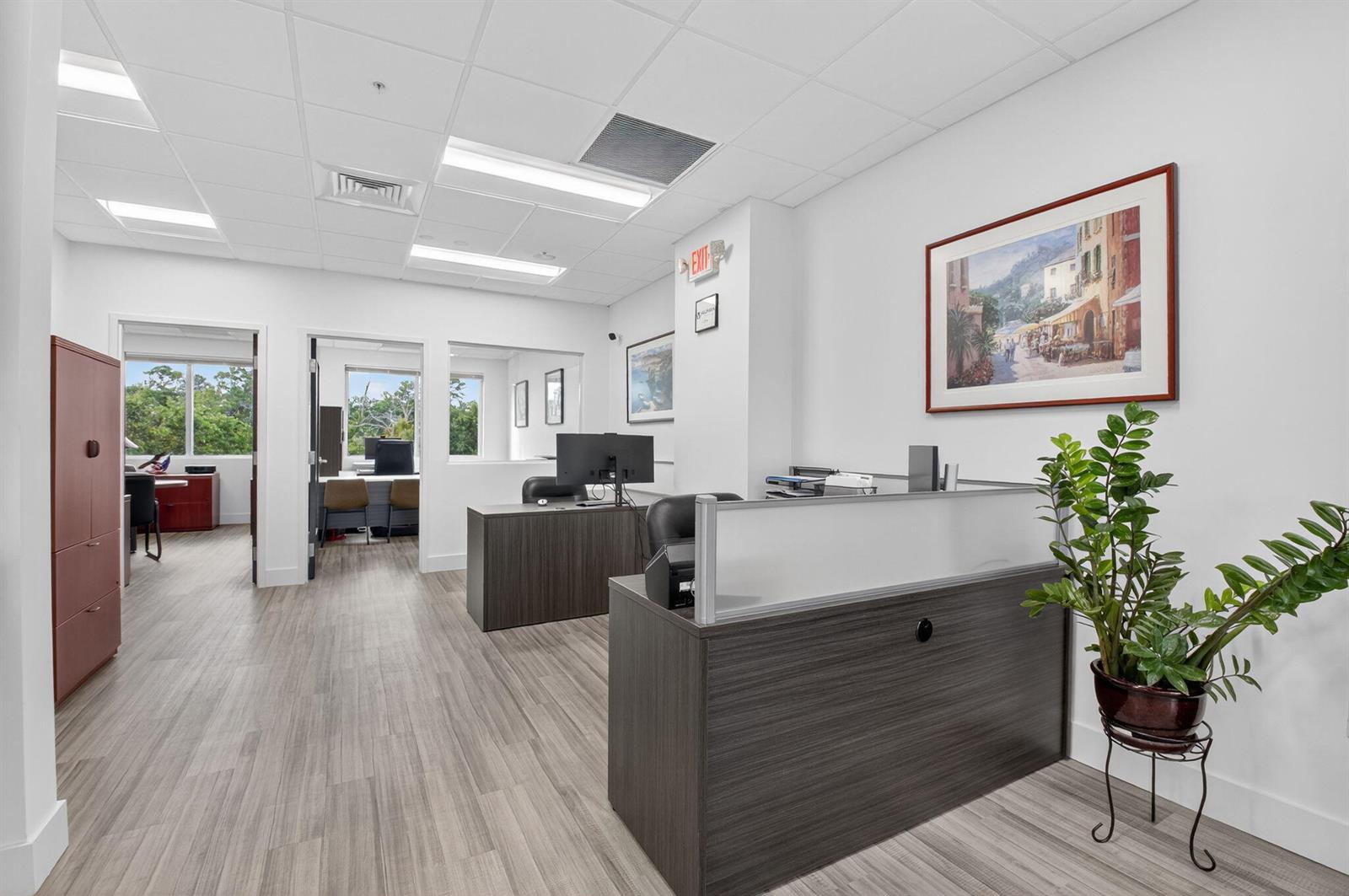 An office interior features a reception desk, wood-look flooring, white walls, and multiple workspaces — 7700 Congress Avenue # 3211, Boca Raton FL 33487, BOCA RATON, FL