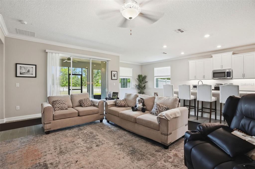 A living room with beige sofas and a kitchen with white cabinets and bar seating — 17135 SHELL BAY DRIVE, LAND O LAKES, FL