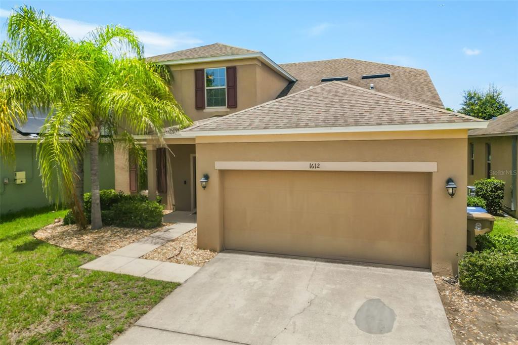 A two-story house with a tan stucco exterior, a two-car garage, and a palm tree — 1612 PINE MARSH LOOP, ST CLOUD, FL