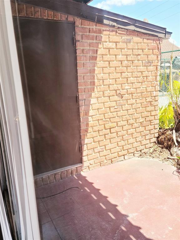 A brick exterior wall with a dark metal door overlooks a small concrete patio area — 2330 HUNTINGTON GREEN CT UNIT 6, ORLANDO, FL