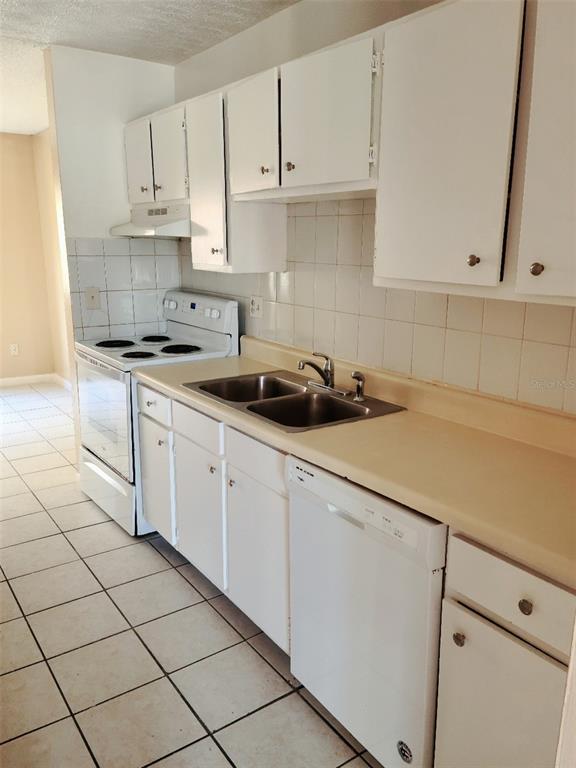 A kitchen features white cabinets, a double-basin sink, a dishwasher, and a white electric stove — 2330 HUNTINGTON GREEN CT UNIT 6, ORLANDO, FL