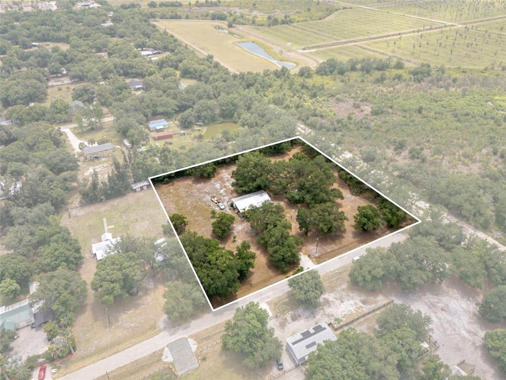 An aerial view shows a rectangular property with a house surrounded by trees and grass — 4981 NW HICKORY STREET, ARCADIA, FL
