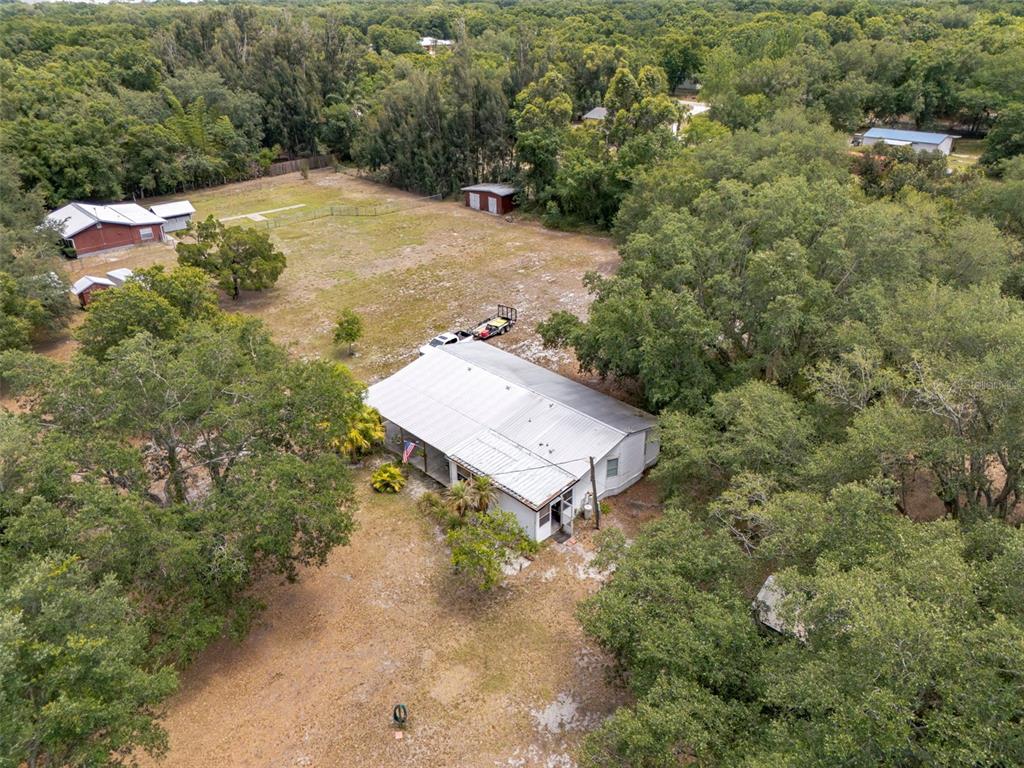 An aerial view shows a house with a metal roof surrounded by trees and grass — 4981 NW HICKORY STREET, ARCADIA, FL