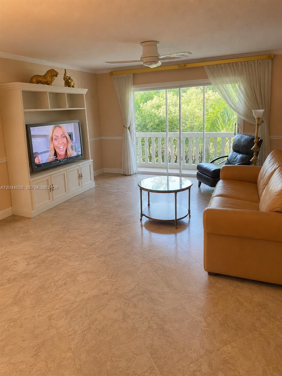 A living room features a beige sofa, a glass coffee table, and a built-in entertainment unit — 219 NE 14th Ave # 306, Hallandale Beach FL 33009, HALLANDALE BEACH, FL